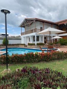 a house with a swimming pool and an umbrella at Refugio de Paz Casa en Anapoima in Anapoima