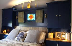 a bedroom with blue walls and a bed with a stained glass window at Top Farm Shepherds Lodge in Marsham