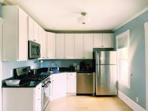 a kitchen with white cabinets and a stainless steel refrigerator at Cozy 1Br Apt in Bangor