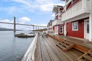 a wooden deck with a building and a bridge at Tjeldsund Tide nr. 6 in Steinsland