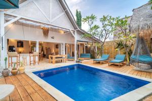 een buitenzwembad met stoelen en een tafel en een huisje bij Villa Satu Cinta in Gili Air