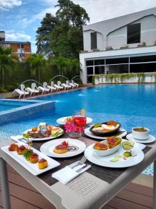 a table with plates of food next to a swimming pool at Hotel Blue 66 in Cali