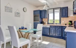 a kitchen with blue cabinets and a glass table and chairs at Maison Proche Mer in Saint-Valéry-en-Caux +11 photos