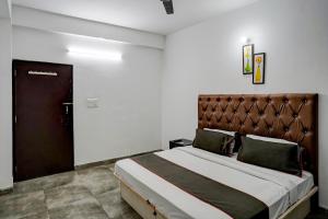 une chambre avec un grand lit avec une tête de lit marron dans l'établissement Super Hotel O Omi Rooms, à Gurgaon