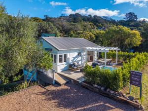 a small white house with a sign in front of it at Marmalade Cottage in Waiheke Island