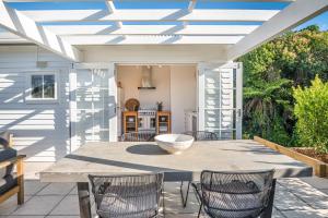 a patio with a table and chairs and a kitchen at Marmalade Cottage in Waiheke Island
