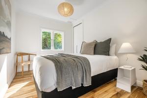 a white bedroom with a bed and a window at Marmalade Cottage in Waiheke Island