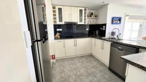 Una cocina con gabinetes blancos y un refrigerador. en Sand N Salt, en Minnie Water