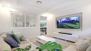 a living room with a couch and a tv on a wall at Albert Fields in Bowral