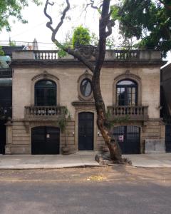 un viejo edificio de ladrillo con un árbol delante de él en Hotel Livin Condesa, en Ciudad de México