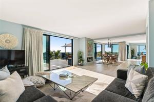 un salon avec un canapé et une table en verre dans l'établissement Island Views - Waihi Beach Holiday Home, à Waihi Beach