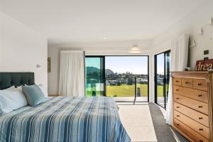 une chambre avec un lit et une porte coulissante en verre dans l'établissement Island Views - Waihi Beach Holiday Home, à Waihi Beach