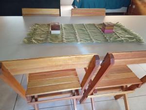 a table with two wooden chairs and a bed at Cabaña Entre Arboles in Tandil