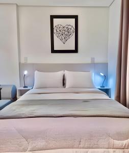 a bedroom with a large bed with a heart picture on the wall at ELEGANtE, Studio Amplo e aconchegante in Curitiba