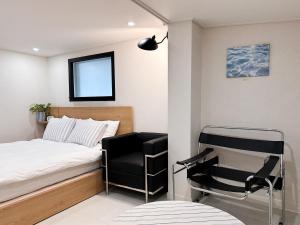 ein kleines Schlafzimmer mit einem Bett und einem Stuhl in der Unterkunft 서울 성북 D'enough House in Seoul