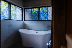 un bagno con una vasca bianca e tre finestre di 古民家宿るうふ 蔦之家 a Koshu