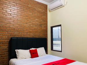a bed in a room with a brick wall at RedDoorz near Jalan Malioboro Area in Ngabean
