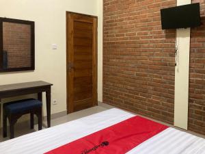 a bedroom with a brick wall and a bed and a desk at RedDoorz near Jalan Malioboro Area in Ngabean +40 photos