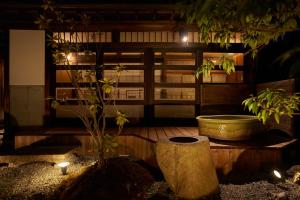 un bagno con vasca, albero e luci di 古民家宿るうふ 蔦之家 a Koshu