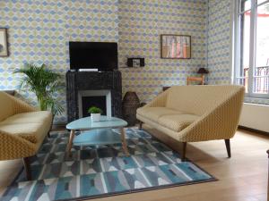 a living room with two chairs and a fireplace at L'Art Du Temps le Gîte in Montreuil-sur-Mer