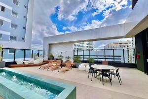 un patio con tavolo, sedie e piscina di AMÁVEl, Studio com Ar Condicionado e Tv Smart a Curitiba