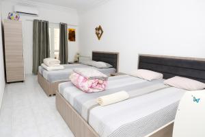 three beds in a room with white walls at Residence Lyne in Kairouan