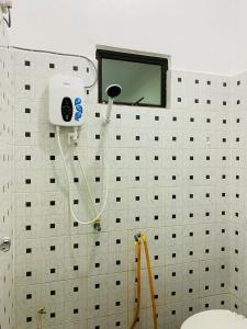 a white tiled bathroom with a toilet and a window at EM Rumah Inap SueKori Jeli in Jeli