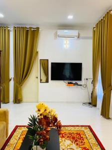 a living room with yellow curtains and a table with flowers at EM Rumah Inap SueKori Jeli in Jeli