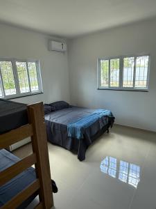 ein Schlafzimmer mit einem Bett und zwei Fenstern in der Unterkunft Malicia Ranch in Lagoa do Boi