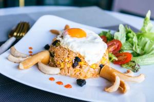 a plate with an egg on top of rice and vegetables at Palace Suite Residence in Phnom Penh