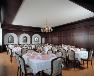 um salão de banquetes com mesas e cadeiras e um lustre em Urlaubshotel Binder em Büchlberg