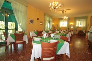 a dining room with tables and chairs and a chandelier at Hotel Vera in Marina di Massa