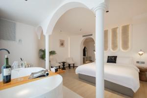 a bedroom with a white bed and a bath tub at Town Designer B&B in Qingdao