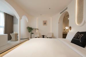 a white bedroom with a large white bed at Town Designer B&B in Qingdao