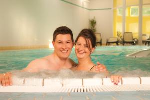 a man and a woman in a swimming pool at Urlaubshotel Binder in Büchlberg