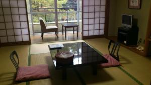 een woonkamer met een tafel en stoelen en een raam bij Daibutsukan in Nara