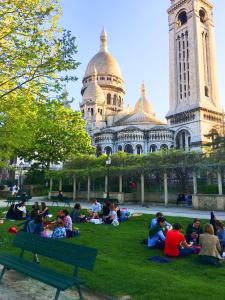 een groep mensen die op het gras voor een gebouw zitten bij MONTMARTRE ROMANTIC - chambres d'hôtes de charme à Montmartre - Paris in Parijs