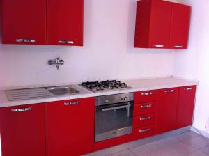 una cucina rossa con piano cottura e lavandino di Casa Jacopo a Torre delle Stelle