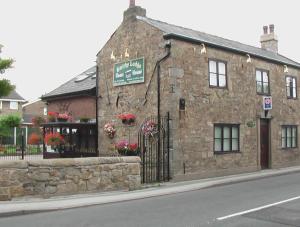 an old stone building on the side of a street at Smithy lodge Guest House in Leyland