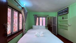 a green bedroom with a bed with a bow on it at Trekking Lodge Nepal in Kathmandu