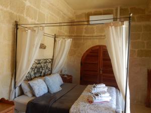 a bedroom with a canopy bed with towels on it at Tas-Suplu Farmhouse in San Lawrenz +21 photos