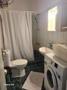 a bathroom with a toilet a sink and a washing machine at IRIA Beach in Iria