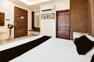 a bedroom with a large white bed and wooden doors at Hotel O Drishti Grand in Lucknow