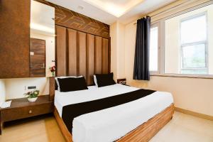 a bedroom with a large bed and a window at Hotel O Drishti Grand in Lucknow