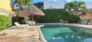 a small swimming pool with a straw umbrella and chairs at Oasis del Mar- Departamento Palma in Progreso