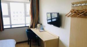 a room with a desk and a tv on a wall at 7 Days Inn Korla Passenger Station in Bayingholin +43 photos