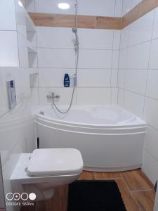 a white bathroom with a toilet and a bath tub at Pokoje nad Radunią - Taras, parter in Pruszcz Gdański +12 photos