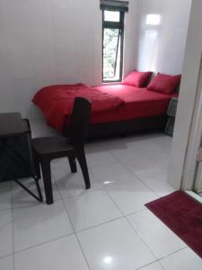 a bedroom with a red bed and a chair at Mgd kos syariah Sentul in Citaringgul 1