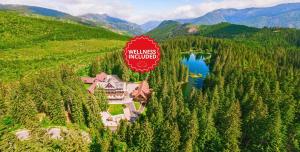 una casa su una collina con un lago e un cartello di Hotel Mikulášska Chata a Demänovská Dolina