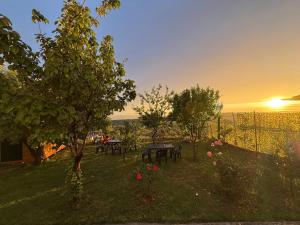 Un jardín con mesas y árboles con la puesta de sol de fondo. en Meti guest house wooden room, en Krujë 8 fotos más